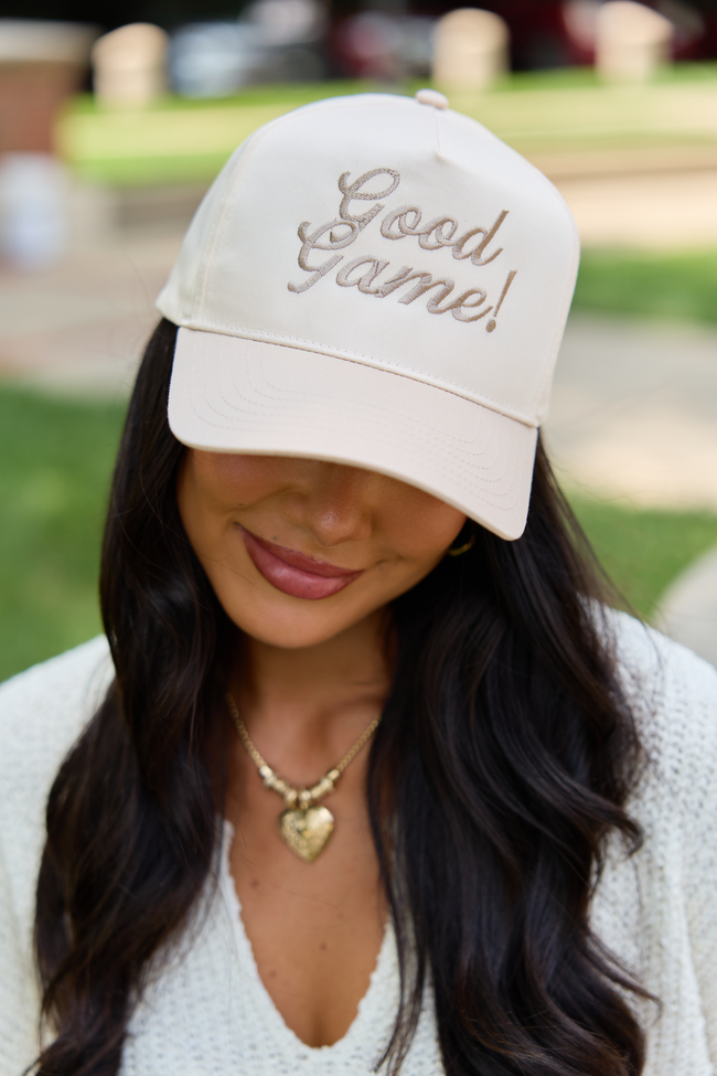 Natural Good Game! embroidered hat worn with a white knit top while holding a football.