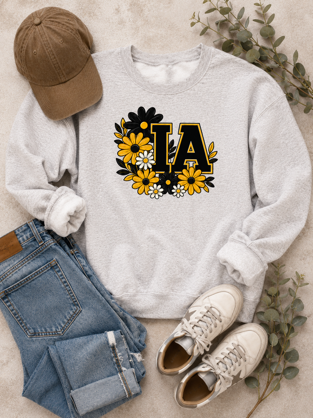 Sand-colored Iowa IA floral sweatshirt styled flat with black joggers, black sneakers and a two-tone cap.