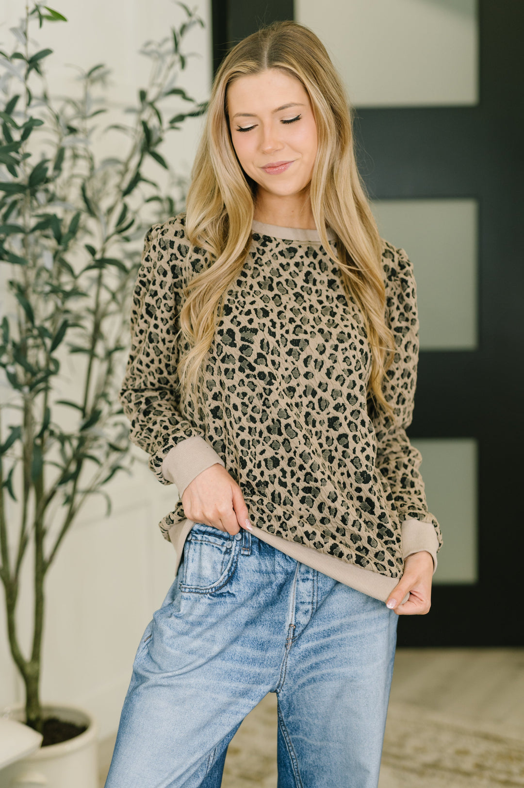 Model wearing a taupe leopard-print long-sleeve top with ribbed trim and blue jeans