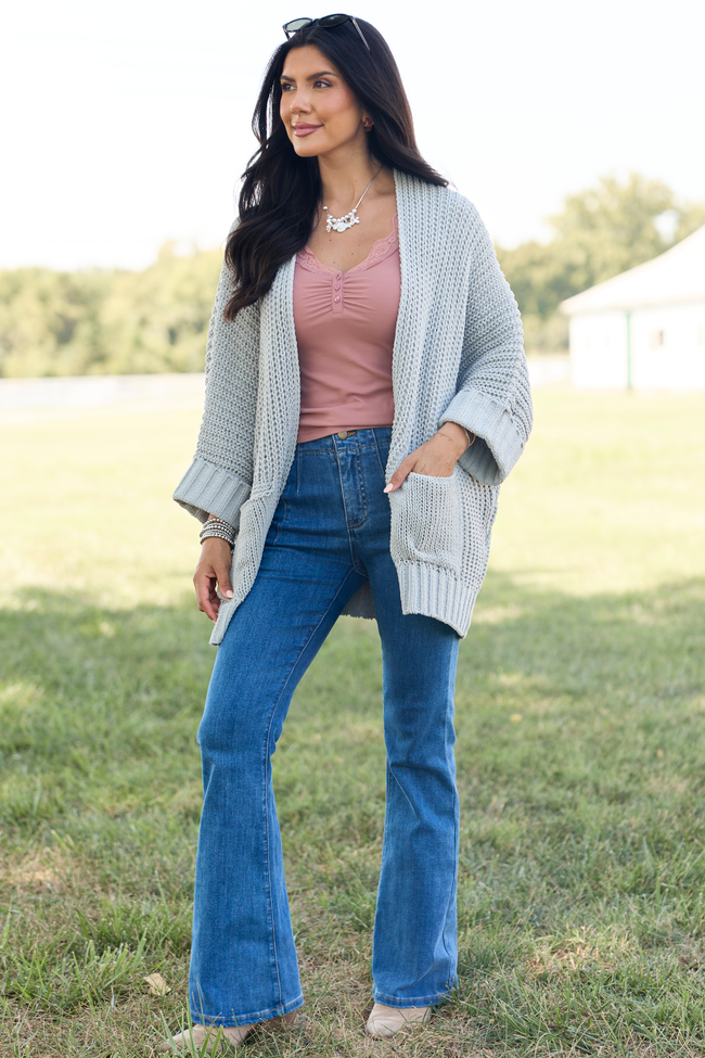 Front view layered over a dusty pink top with jeans — grey oversized open-front cardigan with patch pockets.