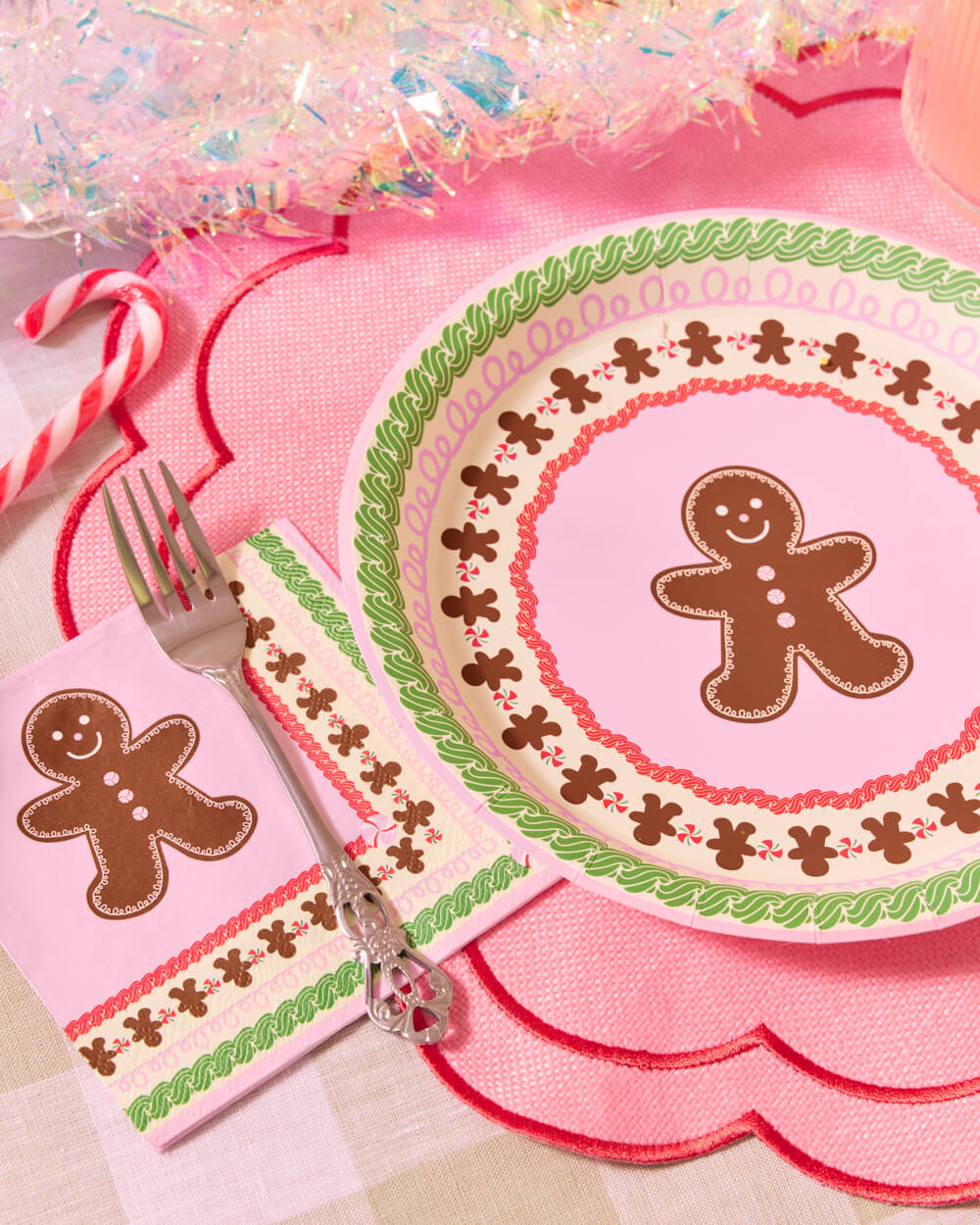 Pink gingerbread plate with a green patterned rim on a scalloped pink placemat.