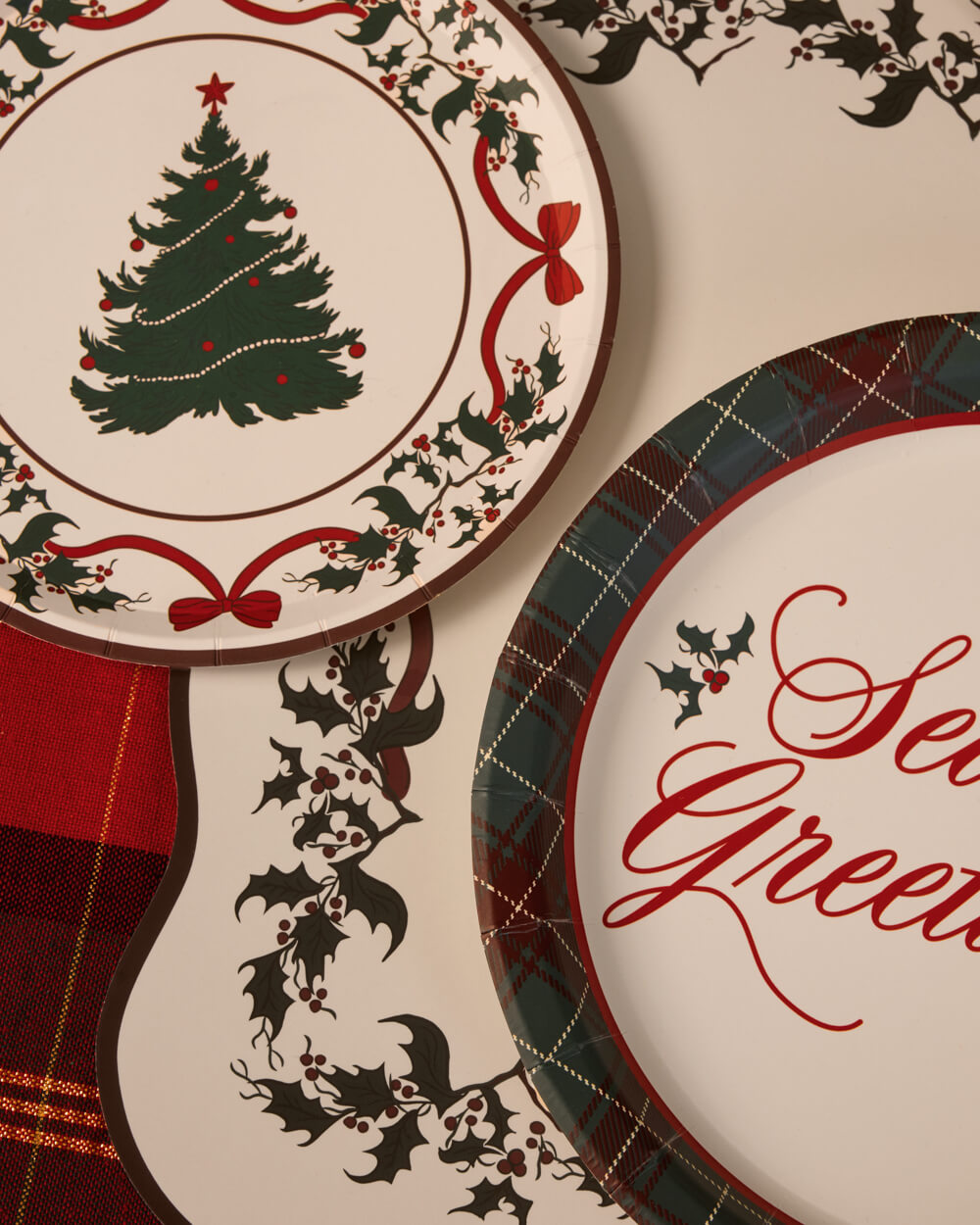 Season's Greetings plaid-rimmed plates paired with Christmas tree plates on a holiday table.