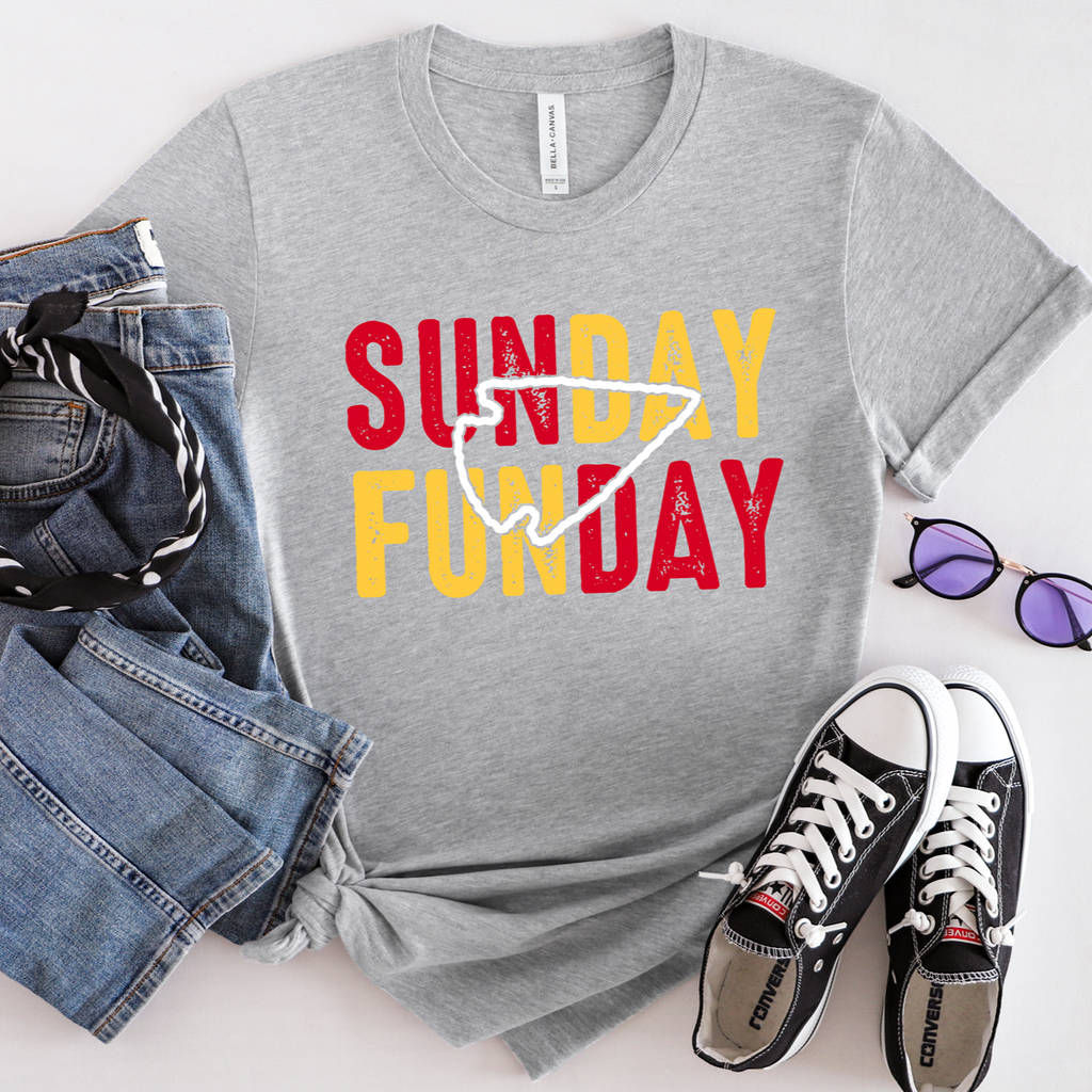 Model wearing a heather gray crewneck with red and yellow Sunday Funday lettering and a white arrowhead outline.